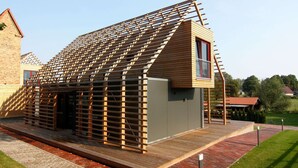 Un bâtiment moderne doté d’un toit en pente et d’un petit balcon.