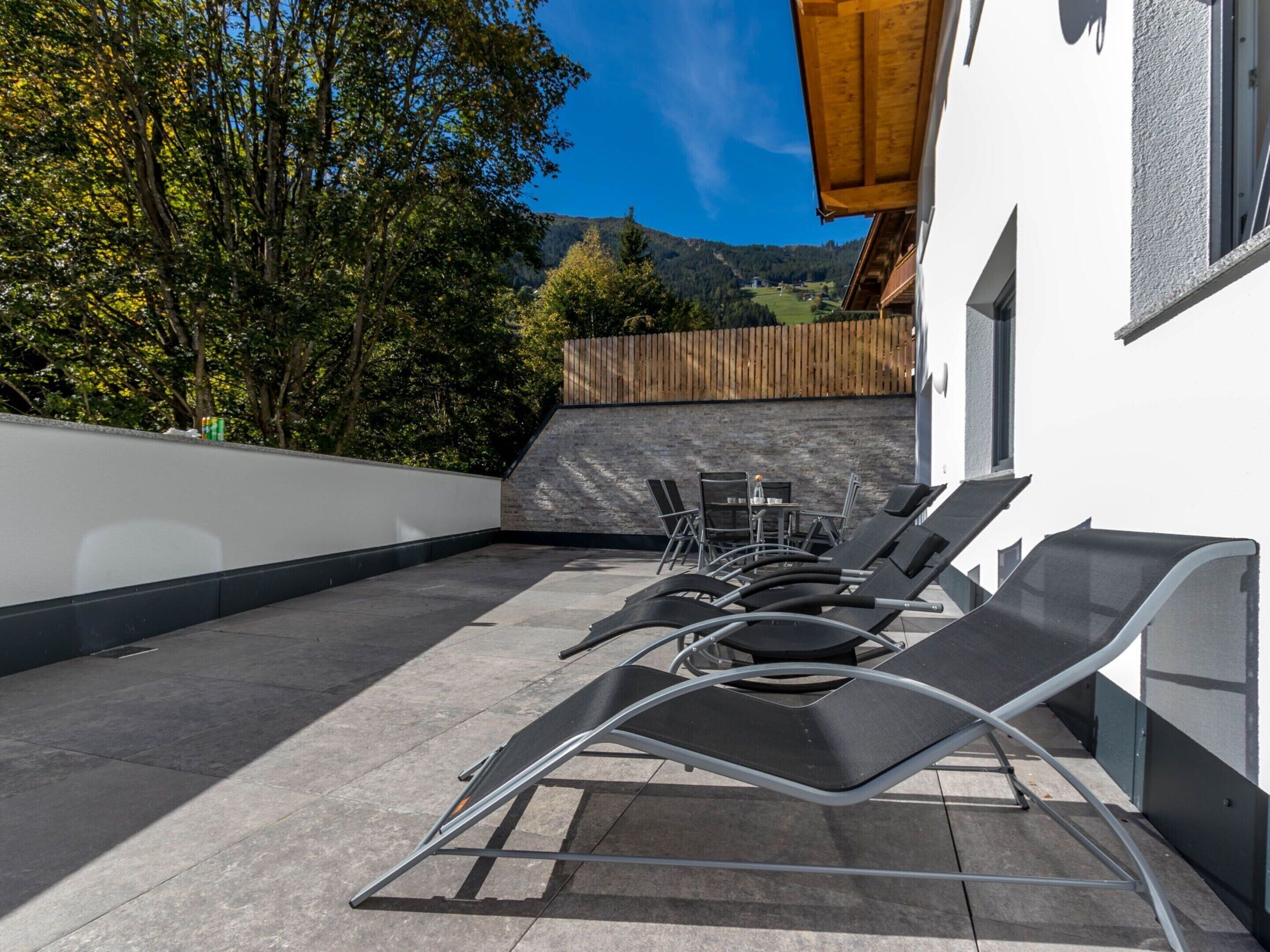 Eine Dachterrasse mit Liegestühlen, einem Tisch und Stühlen.