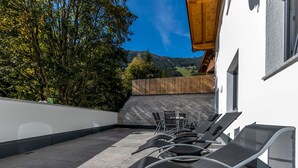 Une terrasse sur le toit, équipée de chaises longues, d’une table et de chaises.