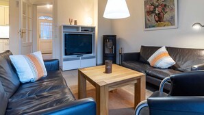 Ein modernes Wohnzimmer mit einer Couch, einem Couchtisch, einem Fernseher und einem Gemälde an der Wand.