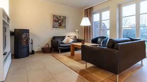 Ein Wohnzimmer mit einer Couch, einem Couchtisch, einem Kamin und einem Fenster mit Vorhängen.