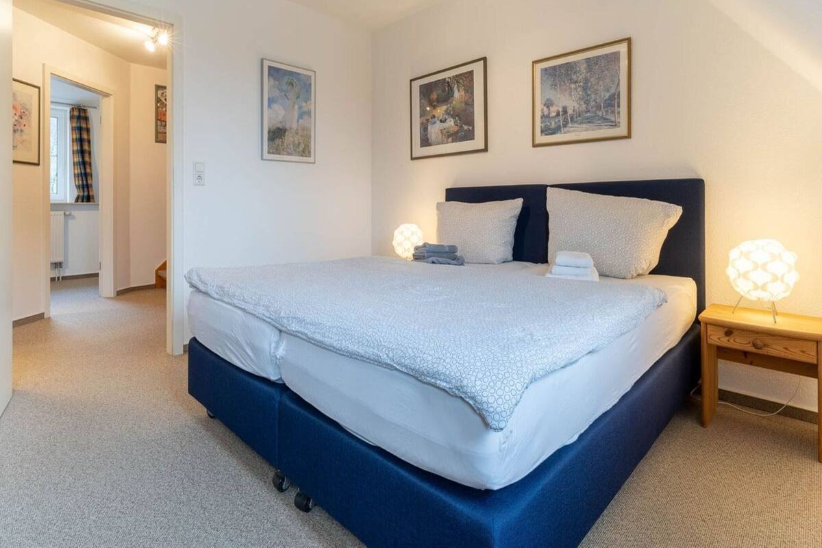 Een slaapkamer met een groot bed, twee bedlampen en drie foto's in lijsten aan de muur.