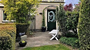 A house with a green door, a balcony, and a garden with a bench. - Homely Apartment in Noordwolde With Balcony (Noordwolde)
