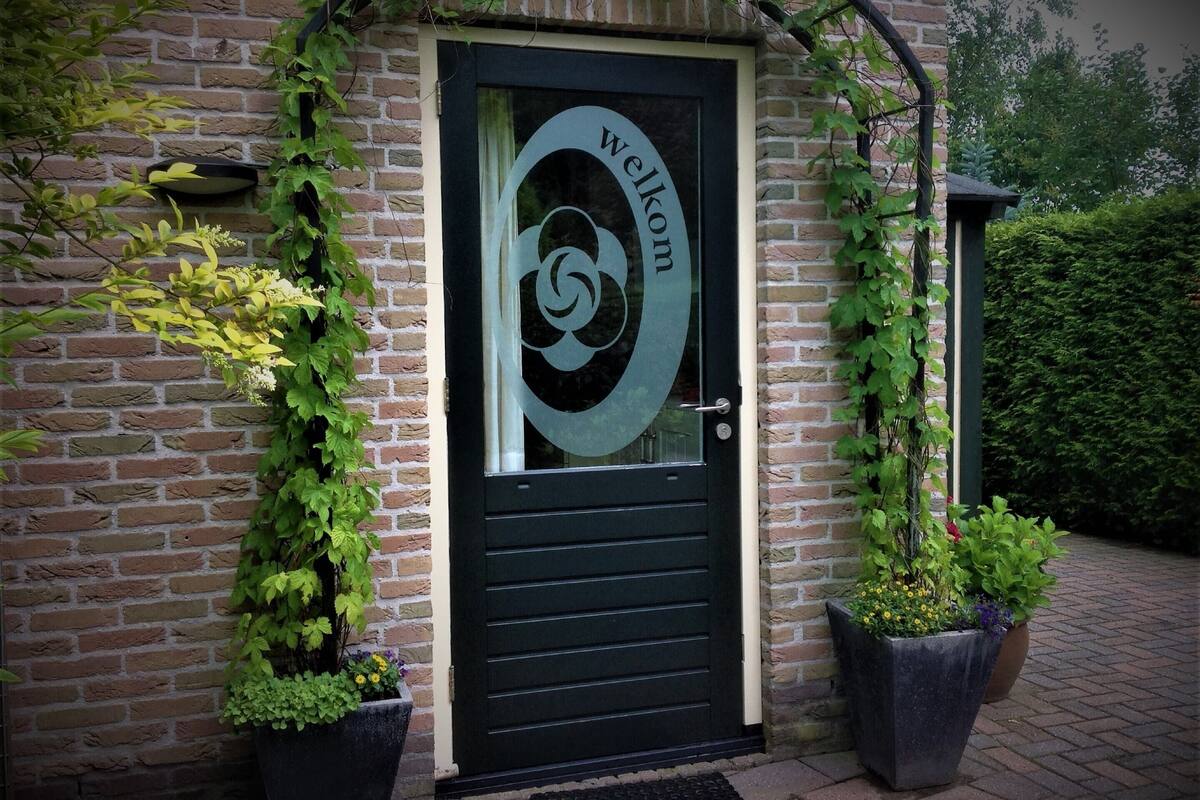 A black door with a glass panel displaying a spiral design and the word "welcome".