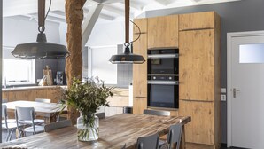 Eine moderne Küche mit Holzausstattung, einem Einbauofen und Pendelleuchten.