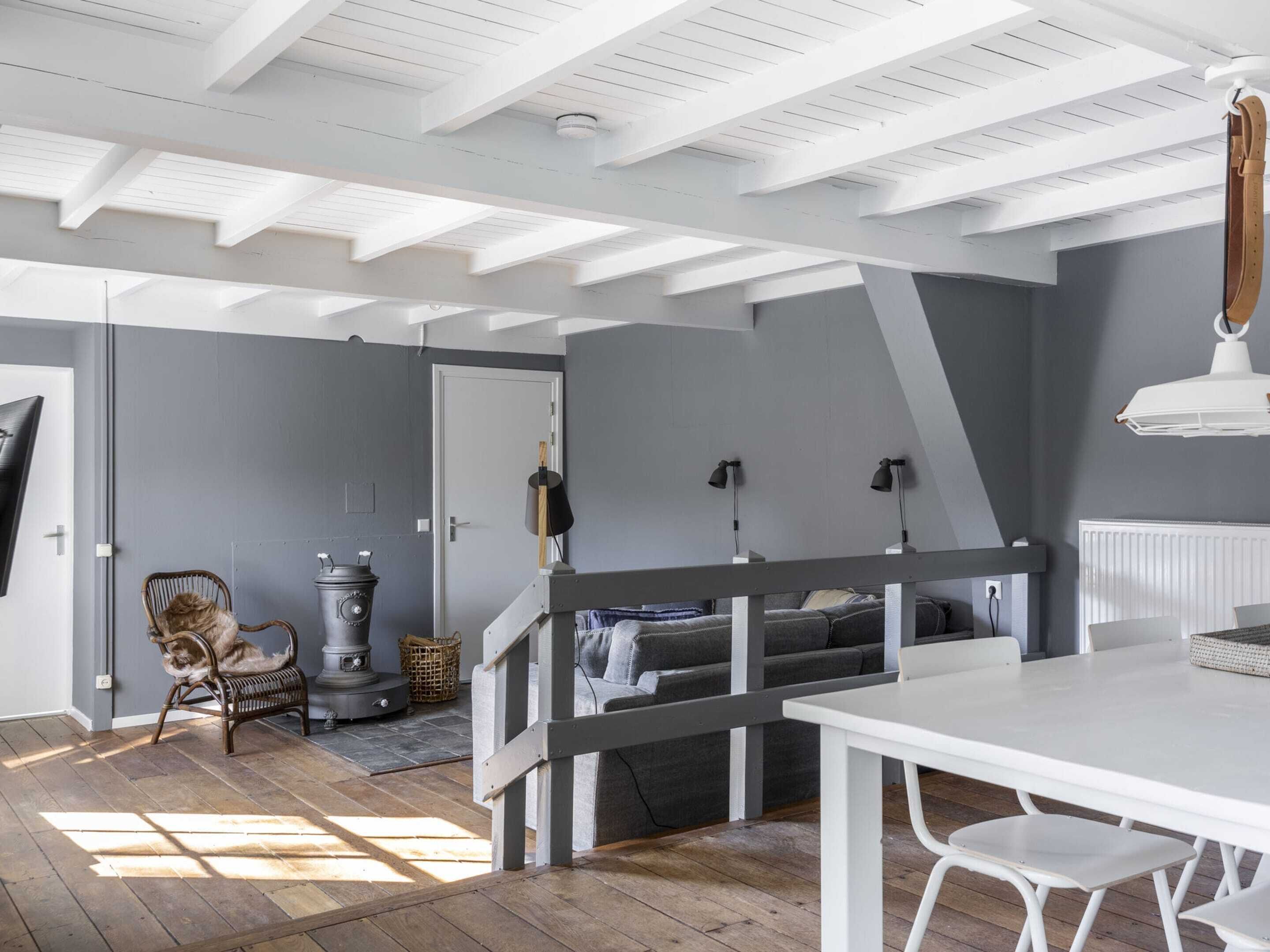 A room with a white ceiling, grey walls, a wooden floor, a white table, and a grey sofa.