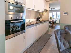 Una cocina moderna con electrodomésticos de acero inoxidable, horno empotrado y un amplio ventanal que proporciona luz natural.