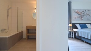 Un baño moderno con bañera, ducha y tocador con espejo.