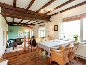 A cozy living room with a wooden ceiling, a dining area with wicker chairs, and a view of the outdoors through a window. - Spacious Mansion in Swolgen With Garden (Swolgen)
