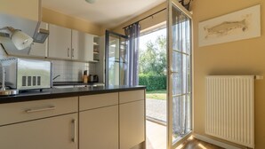 A kitchen with white cabinets, a black countertop, and a window with curtains.