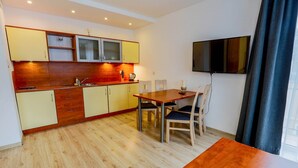 A modern kitchen with wooden cabinets, a dining table, and chairs. - Exquisite Apartment in Miedzyzdroje With Balcony (Międzyzdroje)