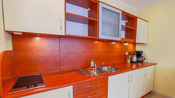 A kitchen with a wooden countertop, a built-in stove, a sink, and white cabinets. - Exquisite Apartment in Miedzyzdroje With Balcony (Międzyzdroje)