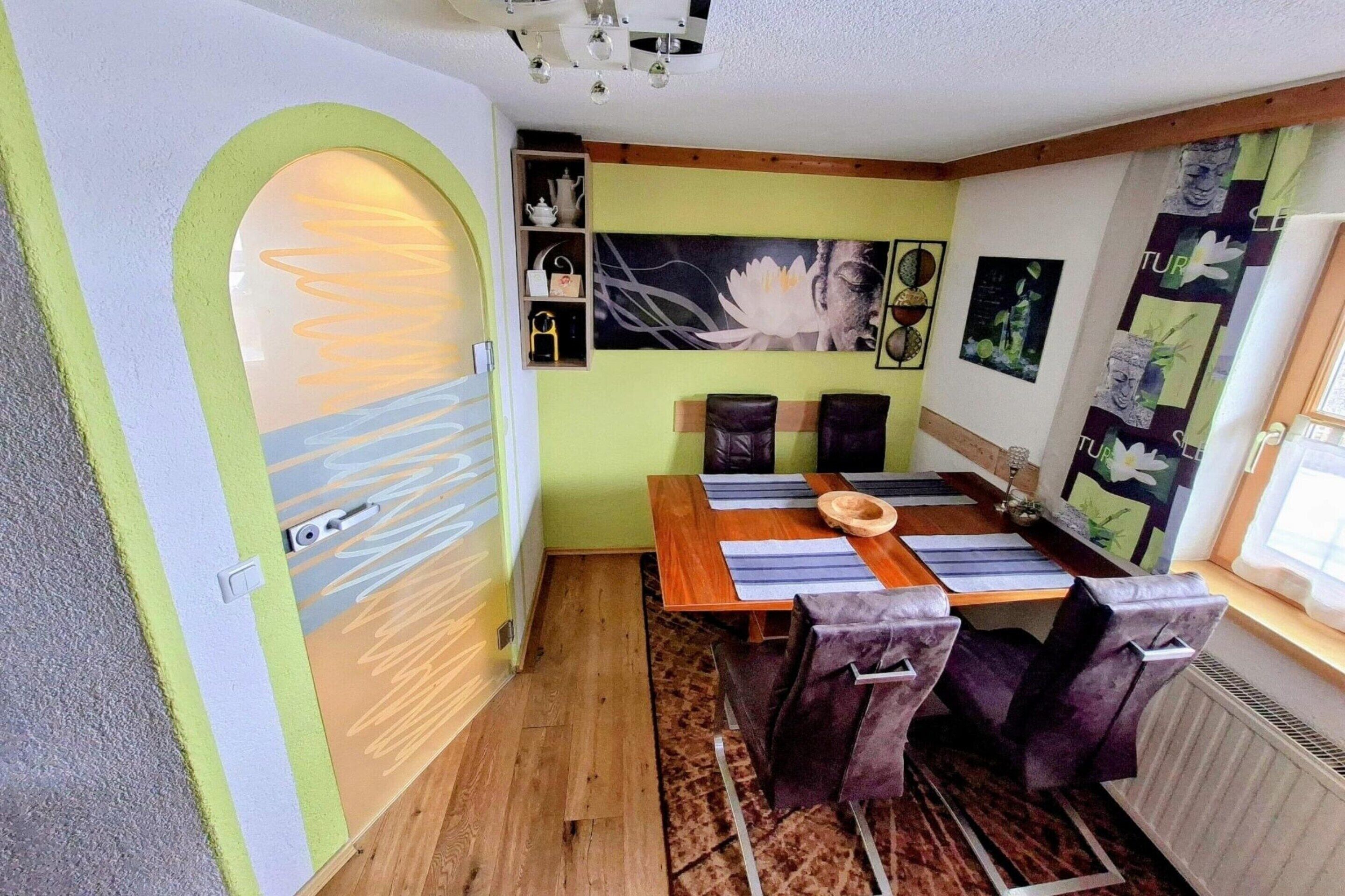 Ein Essbereich mit einem Holztisch, violetten Stühlen und einem großen Blumenbild an der Wand.