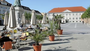 An outdoor café area with tables and chairs, potted plants, and a statue in the background. - Detached Wooden Chalet in Liebenfels / Carinthia Near the Simonhohe ski Area (Liebenfels)