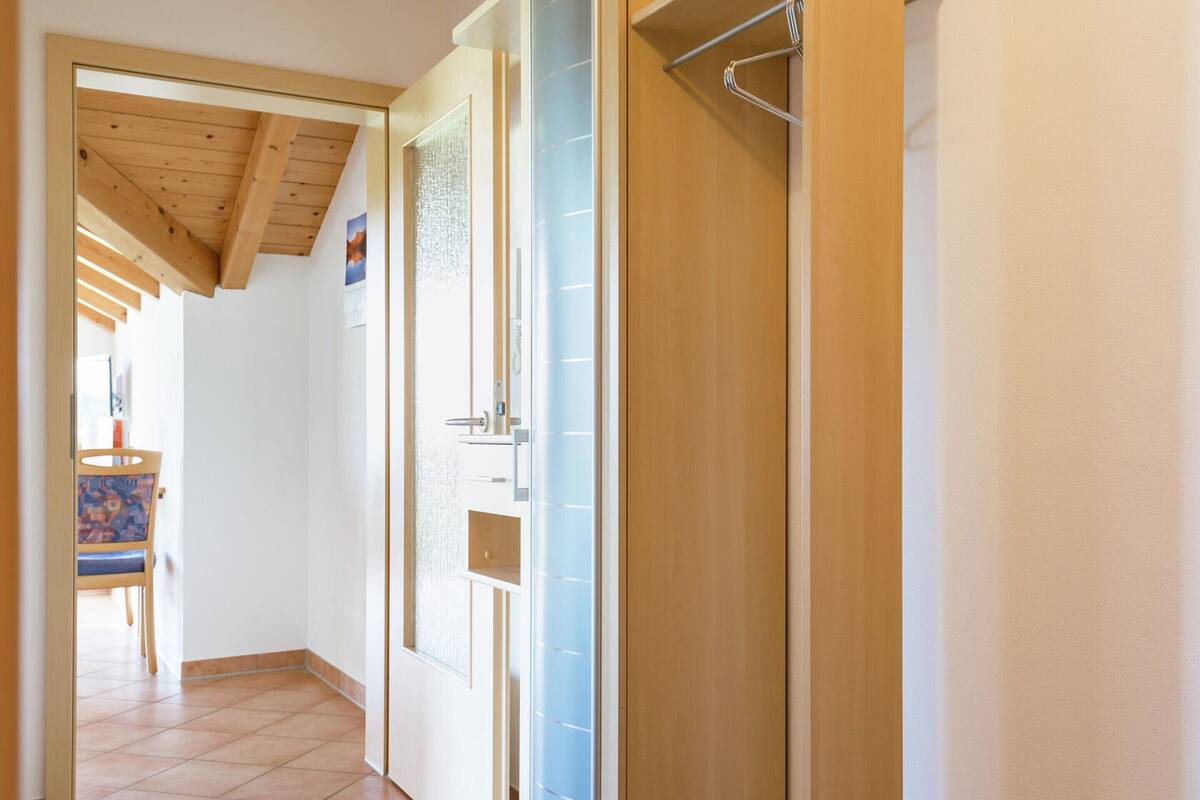 Un pasillo con techo de madera, suelo de baldosas y una puerta con panel de vidrio esmerilado.