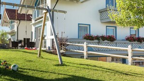 Ein zweigeschossiges Haus mit weißer Fassade, rotem Ziegeldach und Holzzaun.