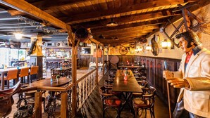 A restaurant with wooden beams, a bar area, and a statue of a man holding a microphone. - Luxury Chalet With Dishwasher, in a Holiday Park in the Middle of De Veluwe (Ede)