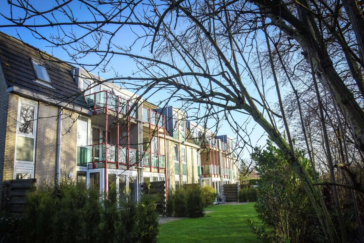 A row of terraced houses with a grassy front yard and trees.