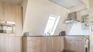 Una cocina moderna con armarios de madera, horno empotrado y ventana que proporciona luz natural.