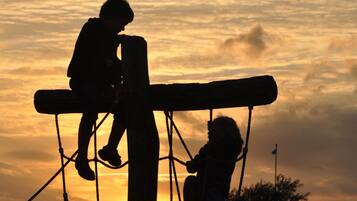 Dos siluetas de personas sobre una estructura contra un cielo al atardecer.