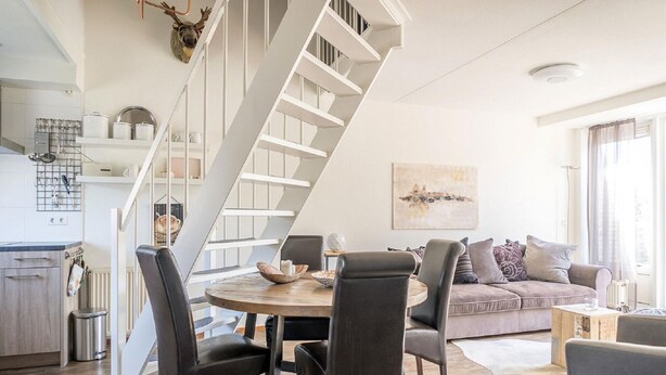 Un espacio habitable moderno con comedor, una escalera y un sofá.