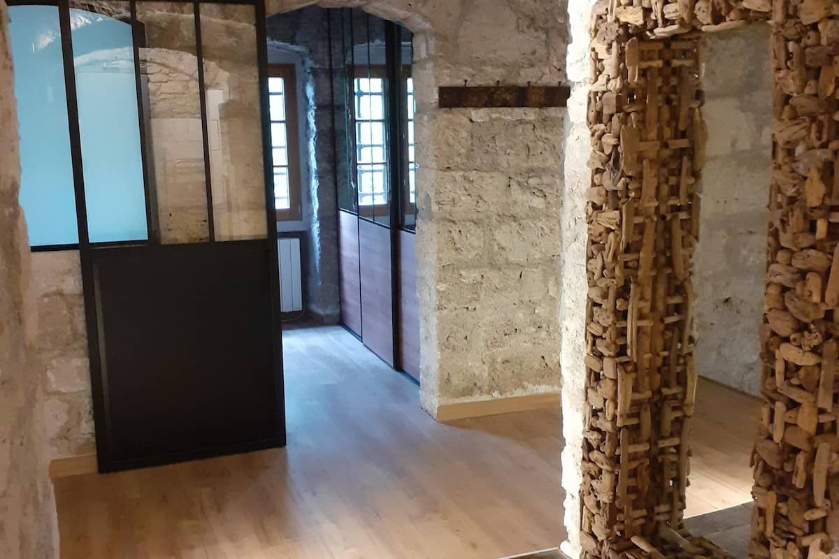 A corridor with stone walls, wooden flooring, and a black door.