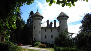 Eine Burg mit zwei Türmen, umgeben von viel Grün und blauem Himmel.