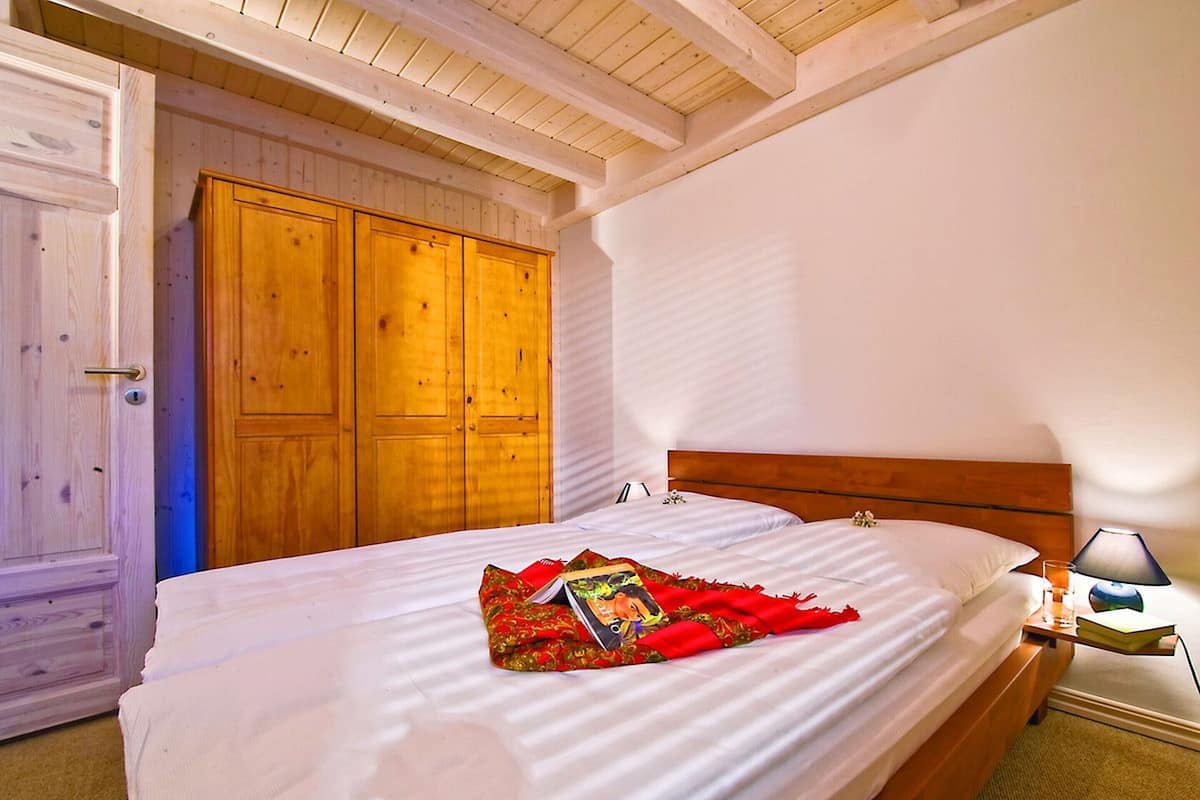 A bedroom with a wooden bed, a nightstand, and a wardrobe.