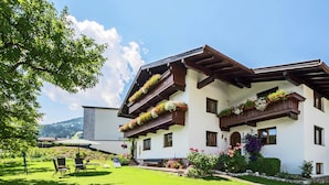 Ein zweistöckiges Gebäude mit Balkonen, die mit Blumen geschmückt sind, einer gepflegten Rasenfläche und freiem Blick auf die umliegende Landschaft.