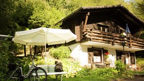 Une cabane en bois rustique dotée d’un balcon, d’un vélo et d’un banc.