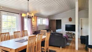 A cozy living room with a wooden dining table, chairs, a sofa, and a television. - 8 Person Holiday Home in Aseral (Aseral)