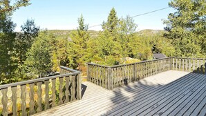 A wooden deck with a railing, surrounded by trees and a hilly landscape in the background. - 8 Person Holiday Home in Aseral (Aseral)