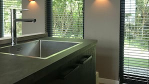 A modern bathroom with a large sink, frosted glass shower enclosure, and two wall-mounted lights. - Semi-detached, Luxury Villa With 3 Bathrooms, sea at 400 m (De Koog)