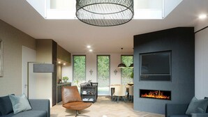 A modern living room with a fireplace, two sofas, a dining area, and a kitchen in the background. - Semi-detached, Luxury Villa With 3 Bathrooms, sea at 400 m (De Koog)