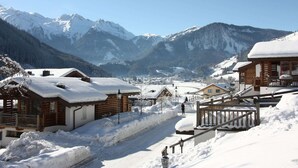 A snow-covered village with wooden houses and a mountain backdrop. - Luxurious Chalet With Sauna in Konigsleiten (Wald im Pinzgau)