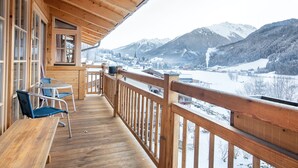 A wooden deck with a view of snow-covered mountains and a lake. - Luxurious Chalet With Sauna in Konigsleiten (Wald im Pinzgau)