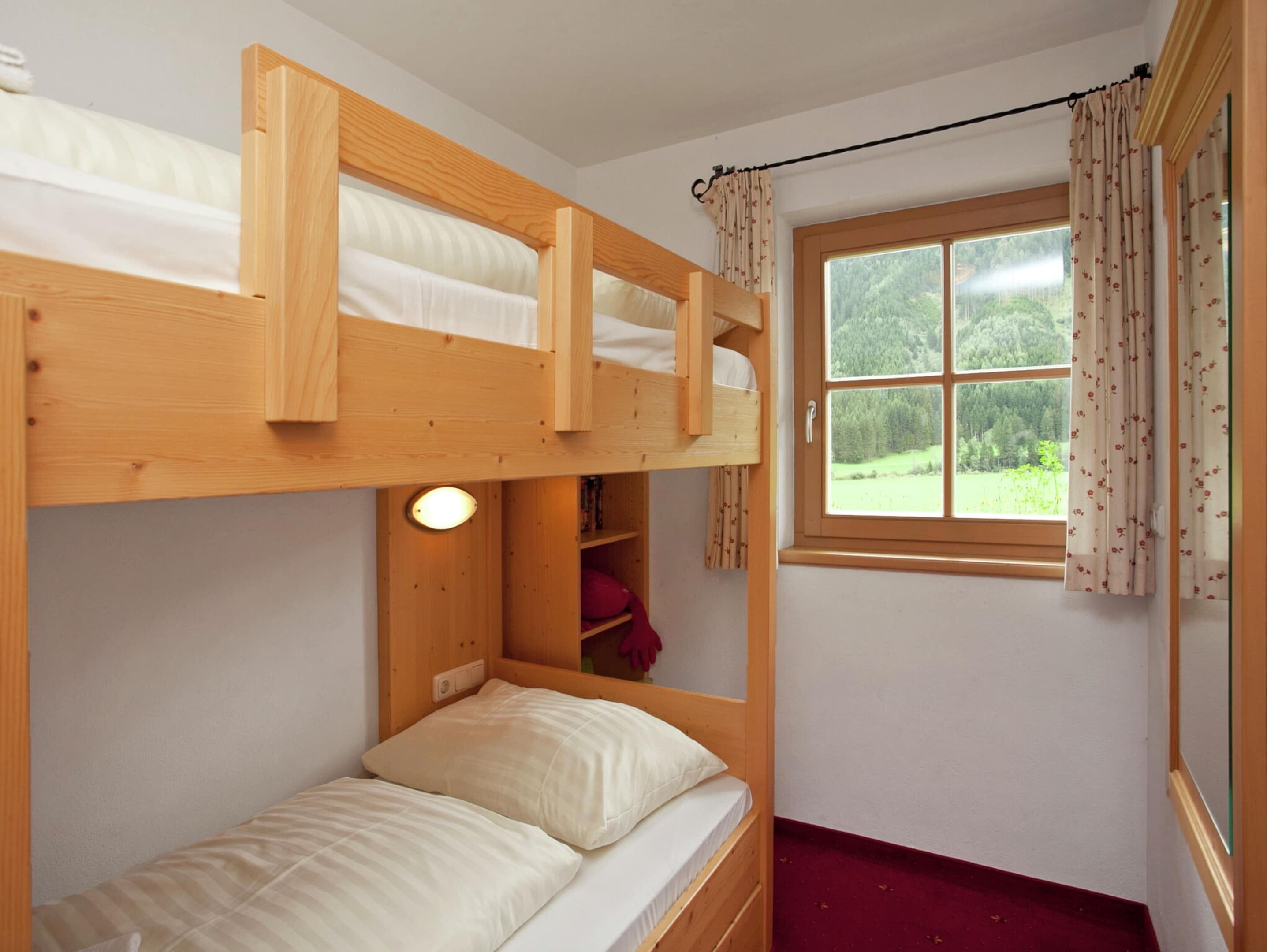 Een slaapkamer met stapelbed, raam en gordijnen.