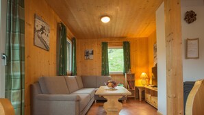 A cozy wooden cabin interior with a sofa, a small table with a bowl of fruit, and a lamp. - Chalet in Annaberg-lungotz With a Community Pool (Annaberg-Lungoetz)