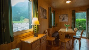 A wooden interior with a dining area, a table with chairs, a bench, and a window with a view of mountains. - Chalet in Annaberg-lungotz With a Community Pool (Annaberg-Lungoetz)