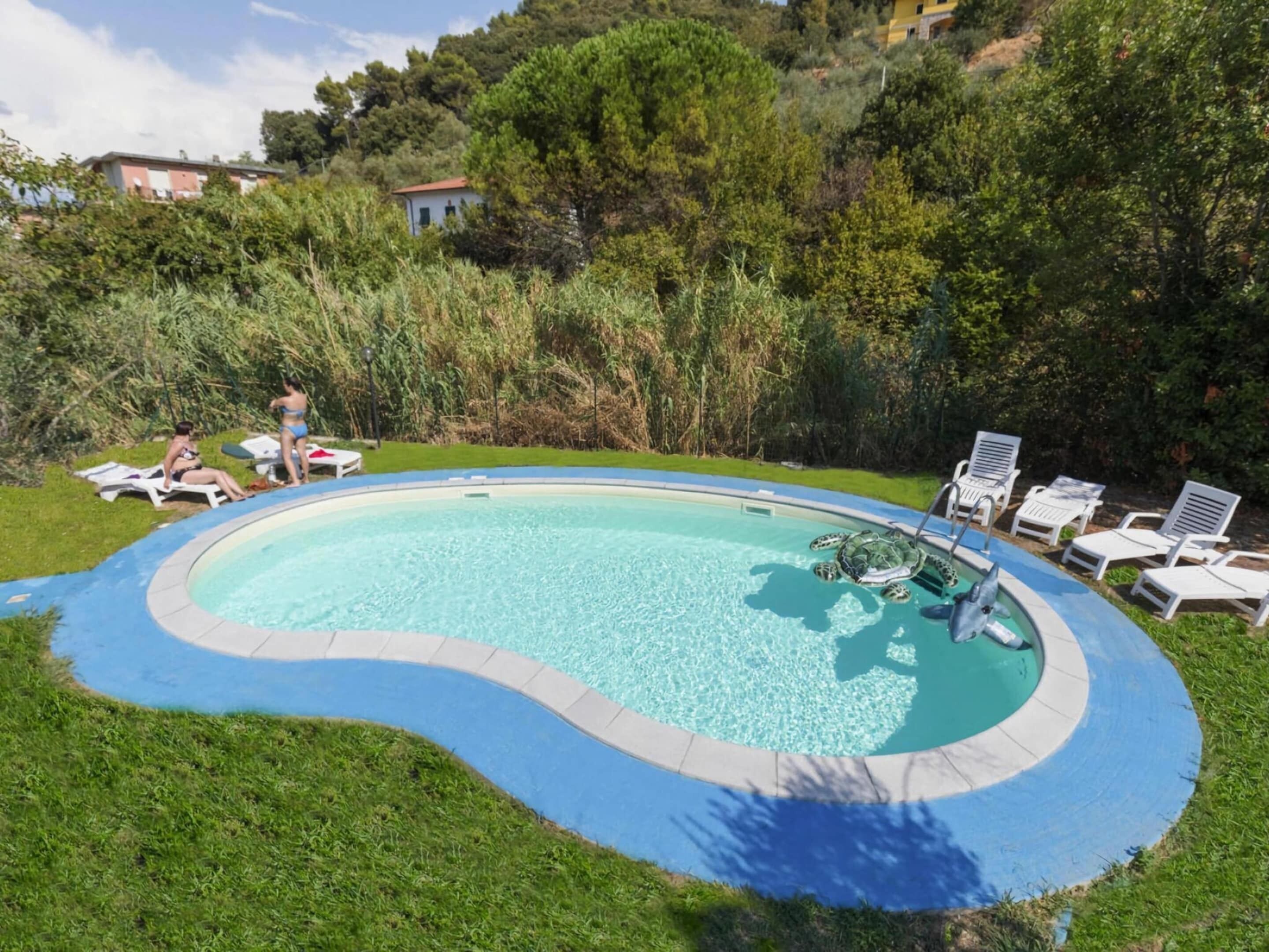 Una piscina con bordo curvo, circondata da erba e alberi.