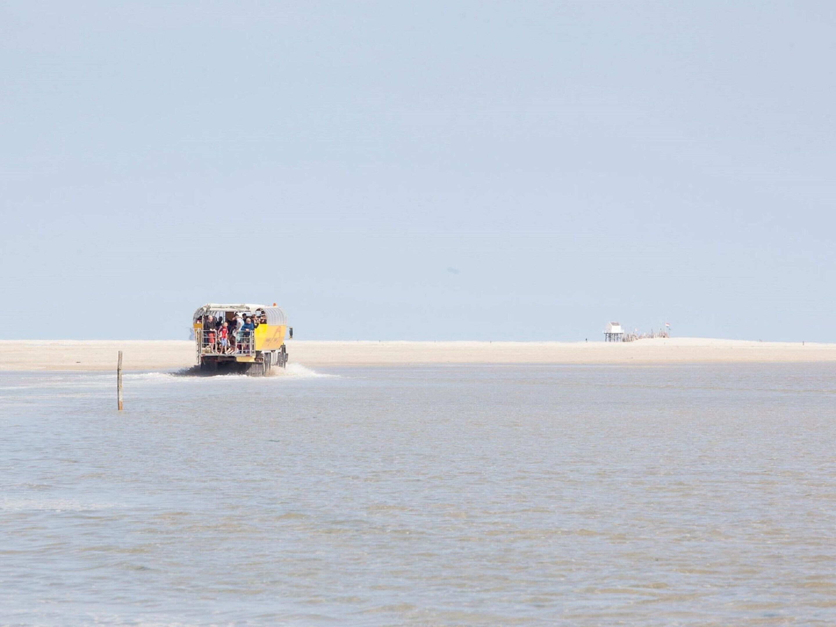 A vehicle on a sandy beach with a clear sky.