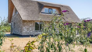 A modern house with a sloped roof, brick walls, and large windows. - Nice Bungalow With Dishwasher in a Holiday Park 1.2 km. From the sea on Texel (De Koog)