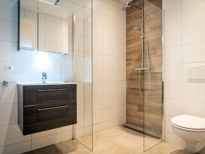 A modern bathroom with a glass shower enclosure, a dark wood vanity, and a white toilet. - Nice Bungalow With Dishwasher in a Holiday Park 1.2 km. From the sea on Texel (De Koog)