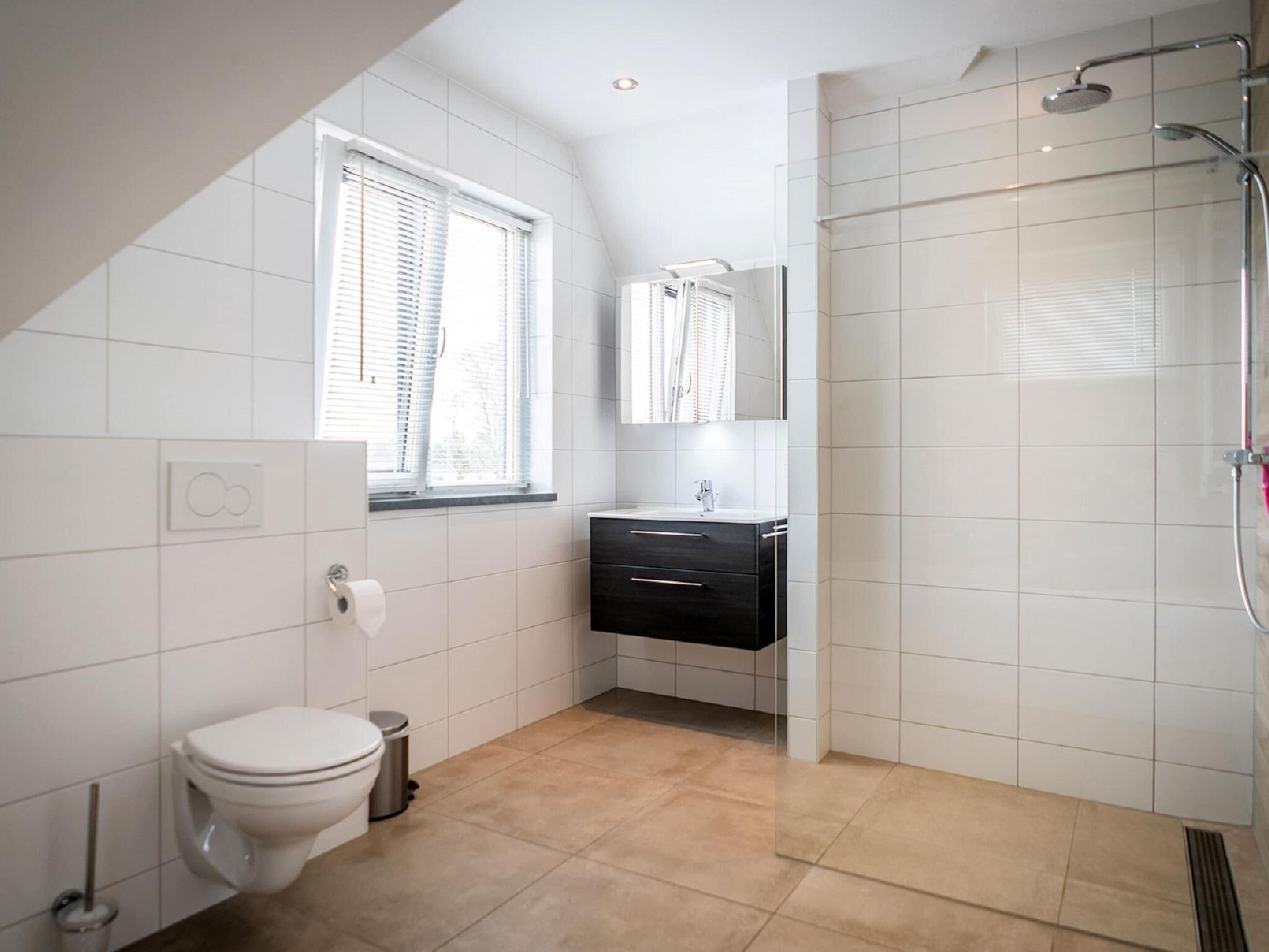 Un baño moderno con inodoro, lavamanos y ducha.