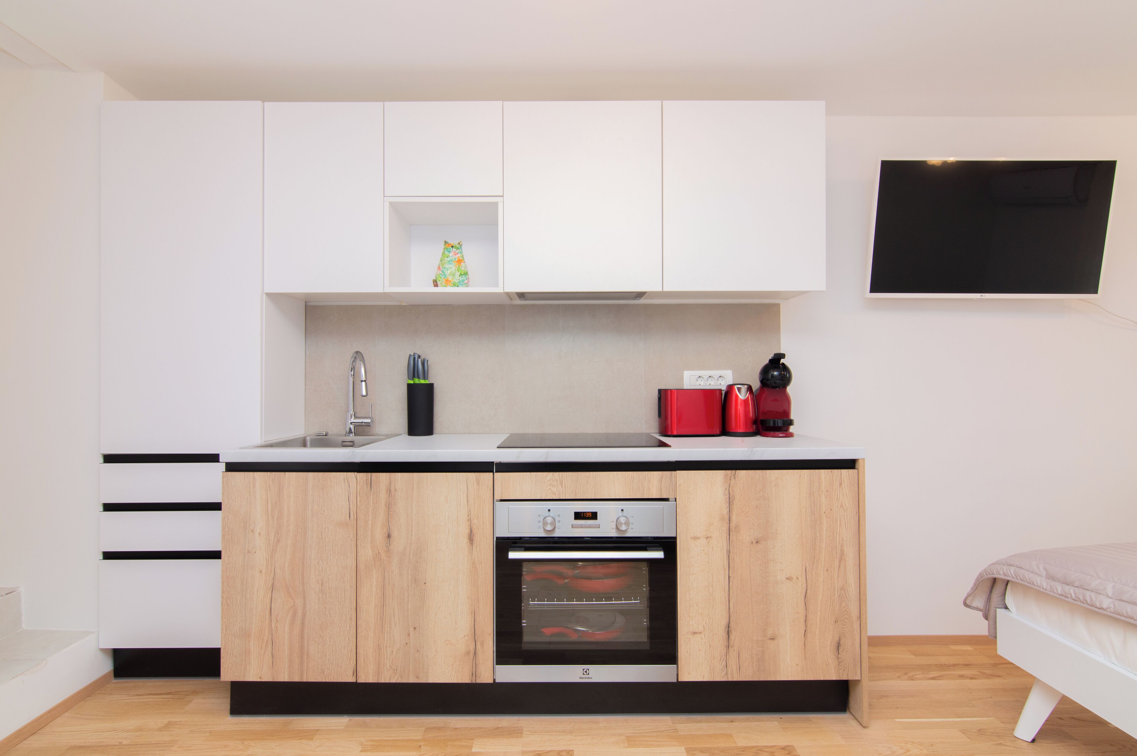 A compact kitchen with white cabinets, a built-in oven, and a small countertop.