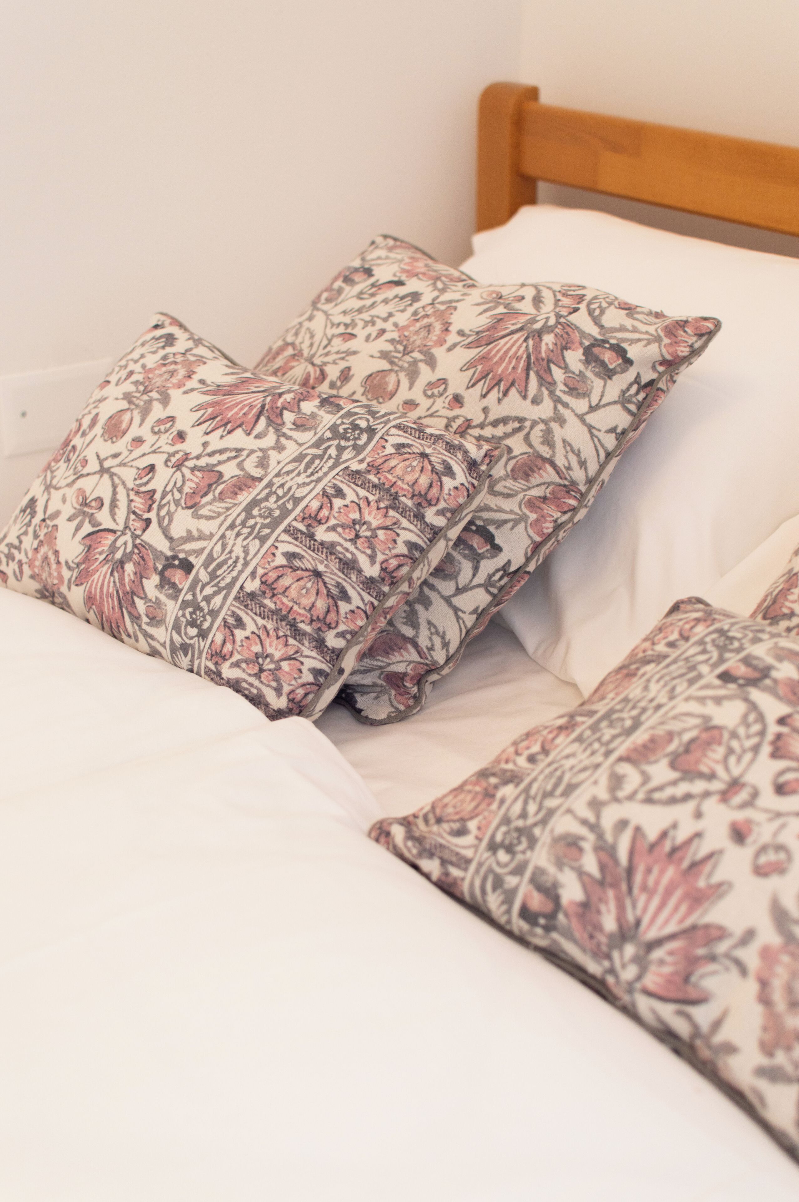 A bed with floral-patterned pillows and a wooden headboard.