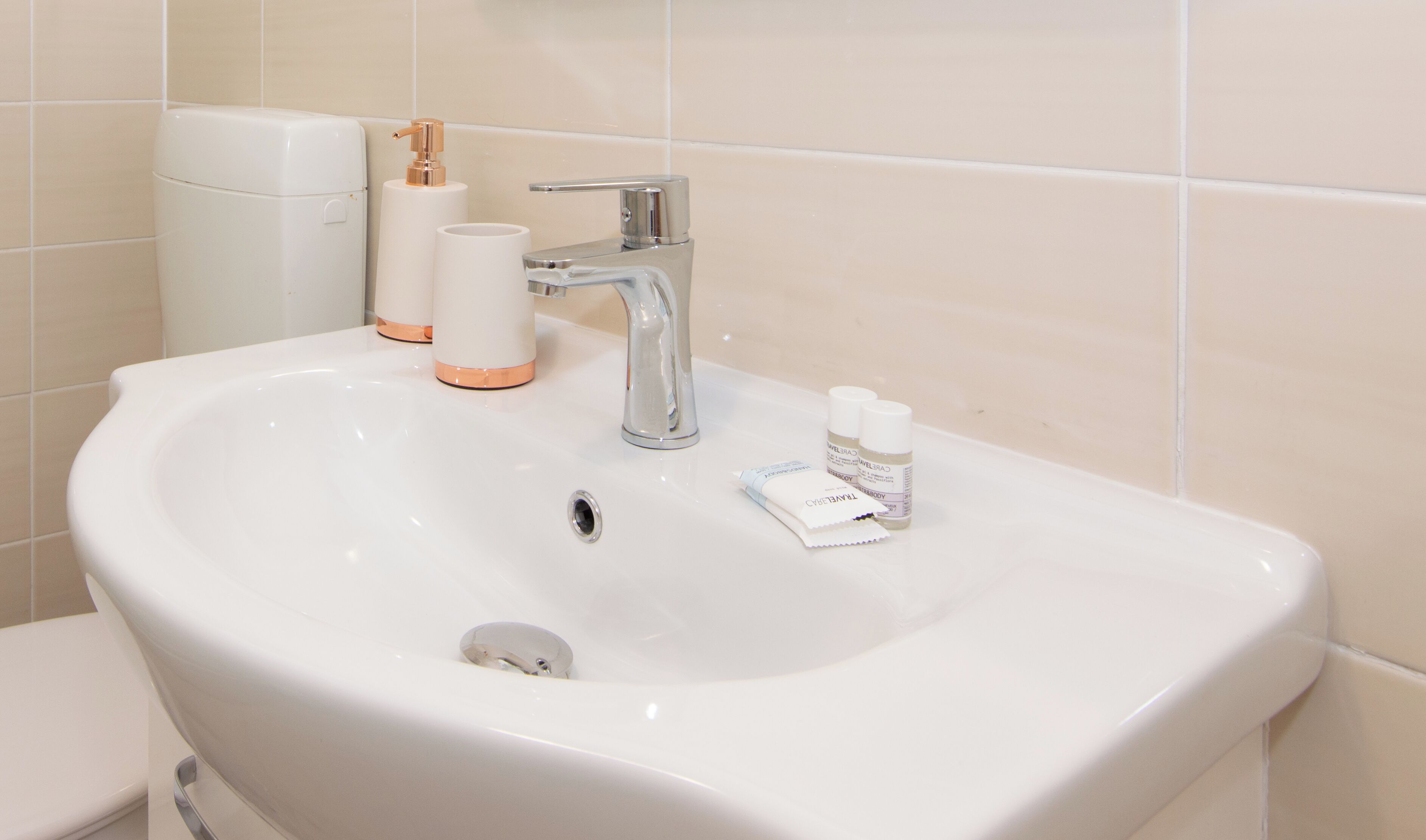 Un lavabo de salle de bain avec un robinet chromé, des toilettes et un distributeur de savon.