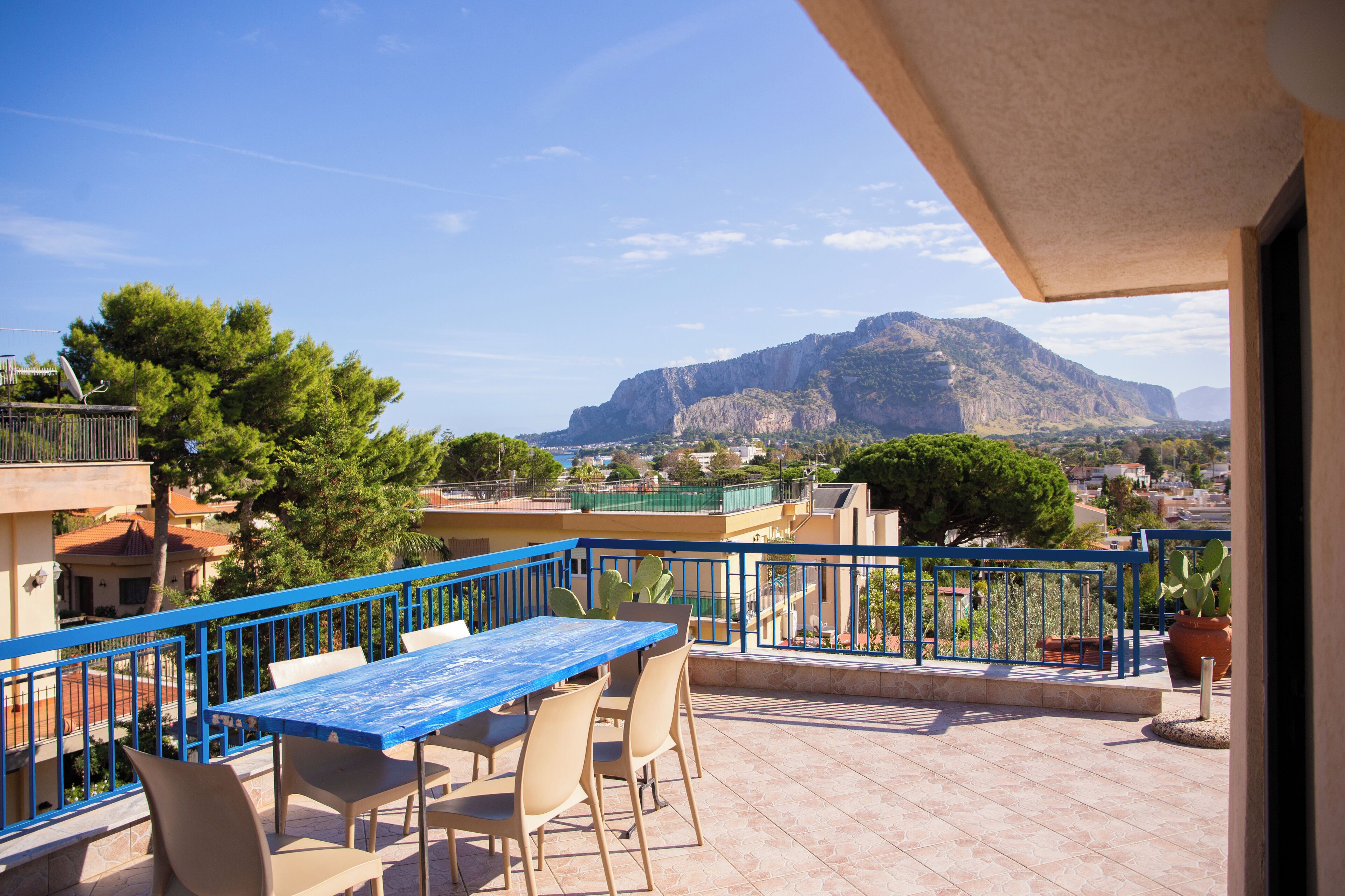 A balcony with a table and chairs, overlooking a mountainous landscape.