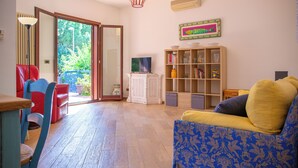 Een woonkamer met een televisie, een boekenkast en een eethoek met stoelen en een tafel.
