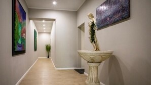A hallway with a marble statue, a painting, and a plant. - HANNIBAL - Design Apartment Lavendel 4 (Wolfsburg)